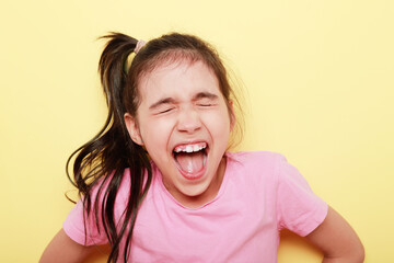 retrato de niña morena con grito de alegría sobre fondo amarillo