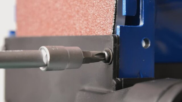 Screw in a screw with the screwdriver on a grinding machine in closeup.