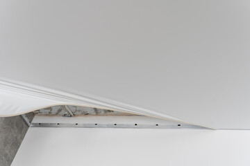 repairmen install stretch ceiling made of pvc vinyl film using a gas heat gun