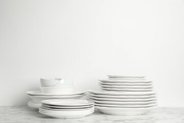 Set of clean plates and bowls on marble table against white background. Space for text