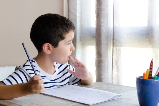 Ni&ntilde;o pensativo mientras hace sus deberes