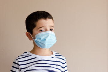 Retrato de chico joven con camiseta de rayas y mascarilla con la mirada perdida