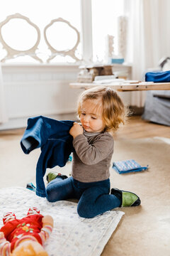 Toddler girl getting dressed in living room