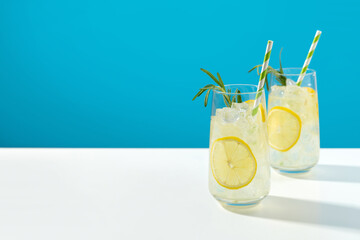 Glass ice lemonade with rosemary on blue background