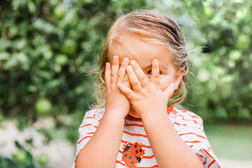 Toddler girl in garden hiding face