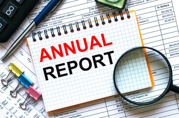 Text Annual Report on notepad with calculator, clips, pen on financial report