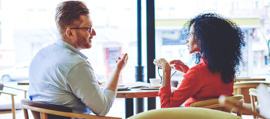 Partnership of intelligent multicultural managers of cafeteria, back view of serious male and female administrators communicate during business meeting on publicity area thinking about solutions