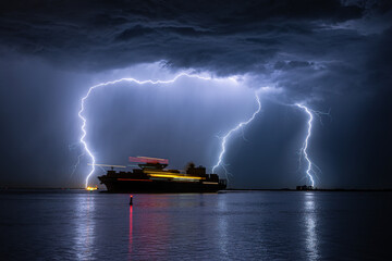 Container ship is leaving the port of Antwerp during a severe thunderstorm - obrazy, fototapety, plakaty