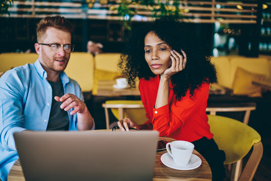 Pensive african american female manager reading information in database on modern laptop computer sitting together with director of cafeteria and discussing creative ideas for development business