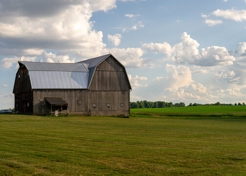 Classic old wood barn in a country field with beautiful clouds