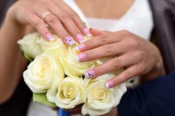 Obraz na płótnie Canvas Wedding manicure on bouquet of white rose. Hands of the bride with ring.