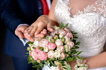 Obraz na płótnie Canvas Wedding bouquet in hands. Husband and wife hands with wedding rings on a bouquet of rose.