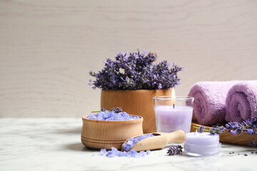 Cosmetic products and lavender flowers on white marble table