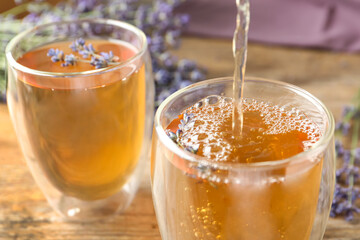 Pouring delicious lavender tea into glass, closeup