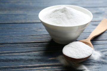Baking soda in bowl on blue wooden table
