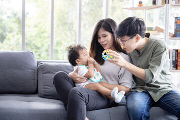 Obraz premium Asian LGBTQ Couple Play with Their Adopted Baby on the Sofa in the Living Room