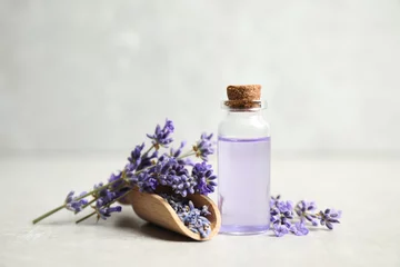  Bottle of essential oil and lavender flowers on light stone table © New Africa