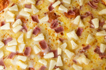 Close up of a hawaiian pizza with pineapple and ham