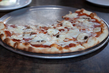 There is pizza in the plate on the table. Sliced pizza. Rest in a cafe.