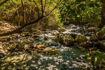The Monachil river trickles past rocks and boulders on the river bed in the Sierra Nevada mountains, Spain in the summertime