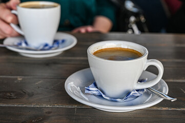 a cup of hot coffee on a table in a cafe. woman holding a cup of white latte.