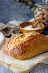 Homemade sourdough bread on a dark table with a napkin, next to flour. Loaf of freshly baked bread close up, vertical background