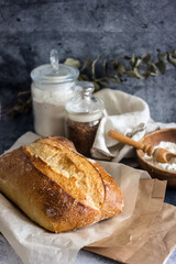 Homemade sourdough bread on a dark table with a napkin, next to flour. Loaf of freshly baked bread close up, vertical background