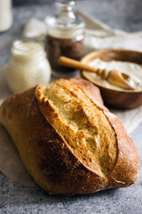 Homemade sourdough bread on a dark table with a napkin, next to flour. Loaf of freshly baked bread close up, vertical background