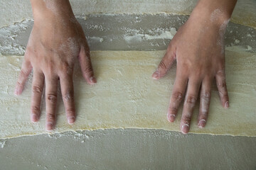 Hands holding a flat fresh piece of dough for ravioli cooking