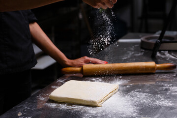 The chef prepares pastries in a professional kitchen. Dark background.