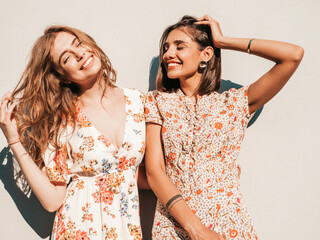 Two young beautiful smiling hipster girls in trendy summer sundress.Sexy carefree women posing near...