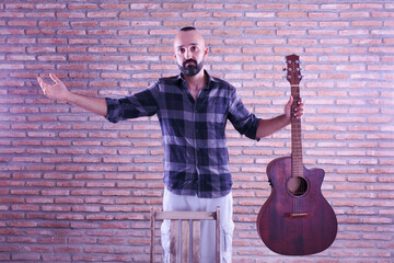 Proud young adult male holding an acoustic guitar after a performance.