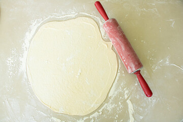 Fresh and raw pizza dough with rolling pin