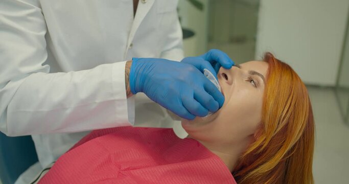 the dentist installs a lip retractor for the patient