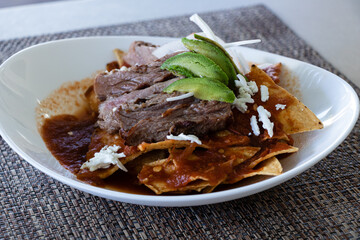 chilaquiles with steak, avocado, onions and cheese