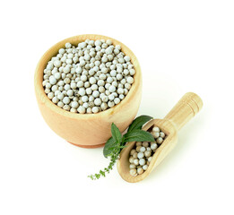 Pepper seeds in a wooden bowl, with a sprig of mint isolated on a white background.