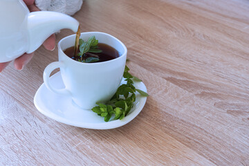 In the upper-left corner, women's hands pour herbal tea from a teapot.