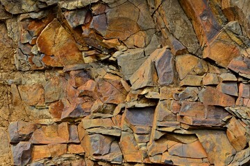 Cracked red rock. Rusty stones with sharp corners and fine red gravel. Plates of red, black and brown stone. Stone ready for mining.