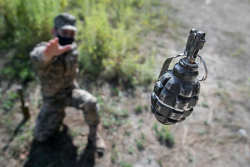 Grenade in flight with safety pin. A soldier in a mask threw a grenade, top view, focus on the...