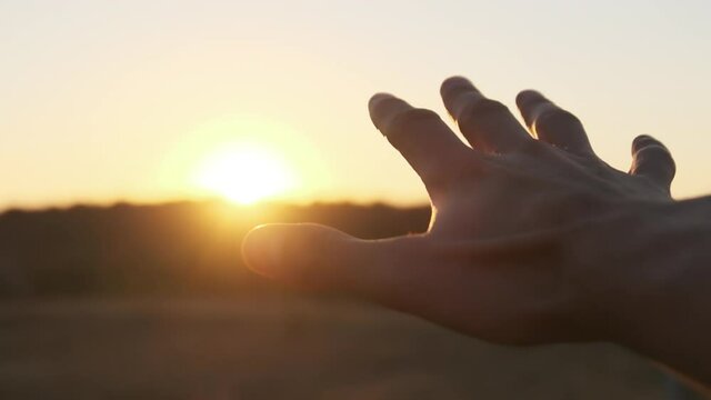 Male Hand against Sunset. Touch the Sun. Sun Shines through fingers. Slow motion