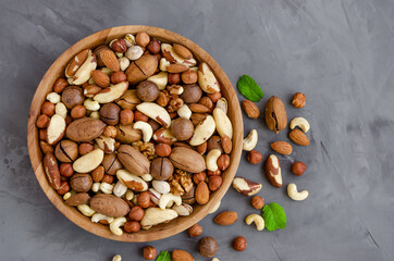 Mix of nuts in a wooden bowl on a dark concrete background.. Healthy food concept. Horizontal, top view, copy space.