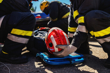 Firefighters taking care of other firefighter and pulling him from crashed car.