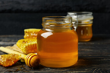 Honeycombs, jar with honey and dipper on wooden background