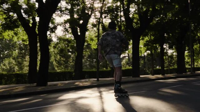 Plano medio  retrato chico moderno caucasico con gafas, gorra negra y camisa colorida moderno con patinando libre  libertad hipster estilo luz y sombras sonriendo bosque verde oscuro baialndo