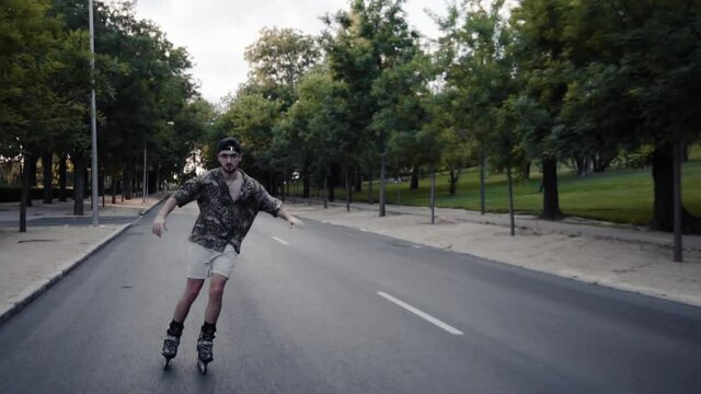 Plano medio retrato chico moderno caucasico con gafas, gorra negra y camisa colorida moderno con patinando libre  libertad hipster estilo en el bosque luz y sombras sonriendo