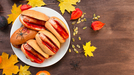 Halloween food. Homemade hot dogs with bloodied fingers on a wooden table for Halloween. Side view. Copy space.