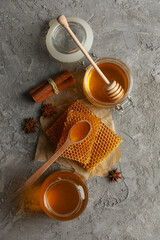 Composition with honeycombs, honey and cinnamon on gray background