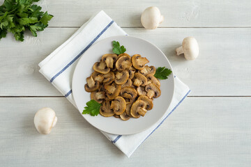 Appetizer of fried mushrooms on a light plate on a napkin. Delicious vegetarian food flat lay on a white wooden background.