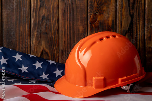 American flag and safety helmet on wooden background, space for text
