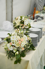 Catering on the event: flowers and white plates on the table